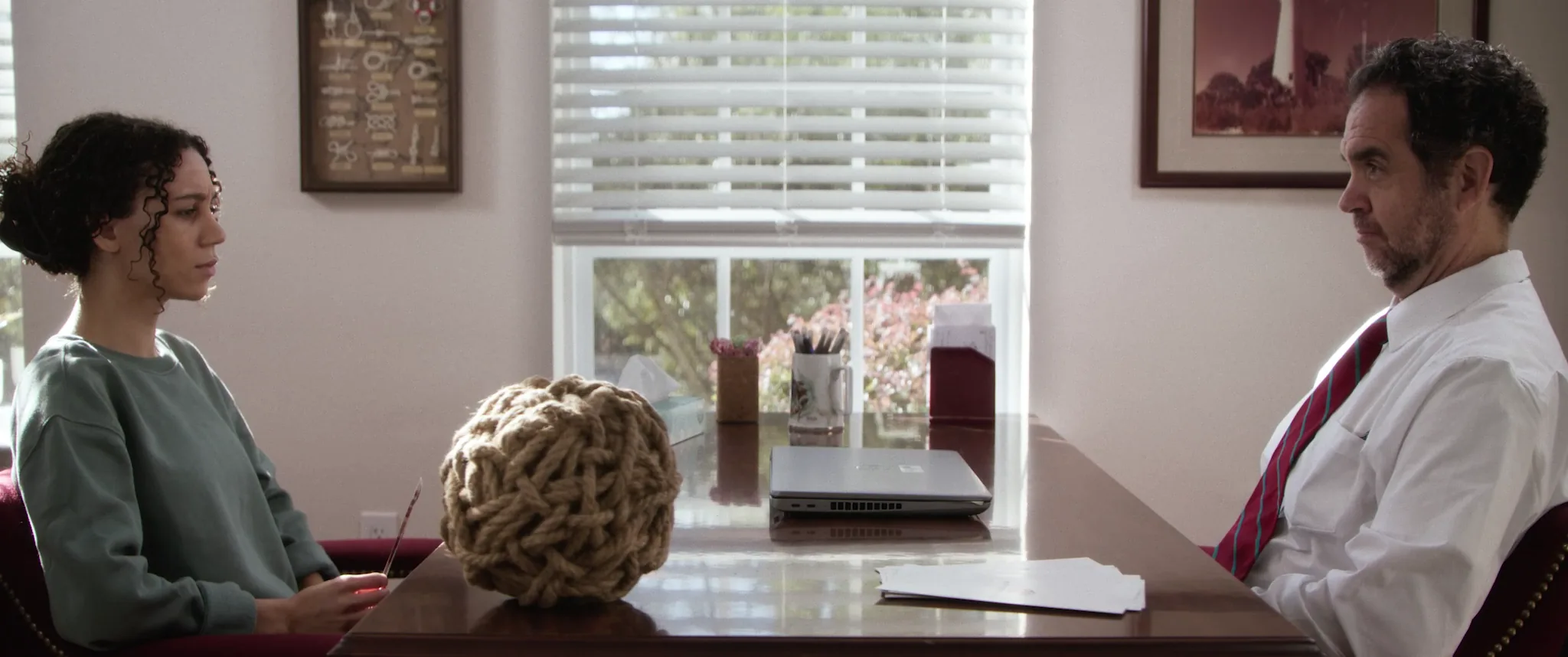 A patient and a doctor across a desk during a consultation, a frame from Afterlife